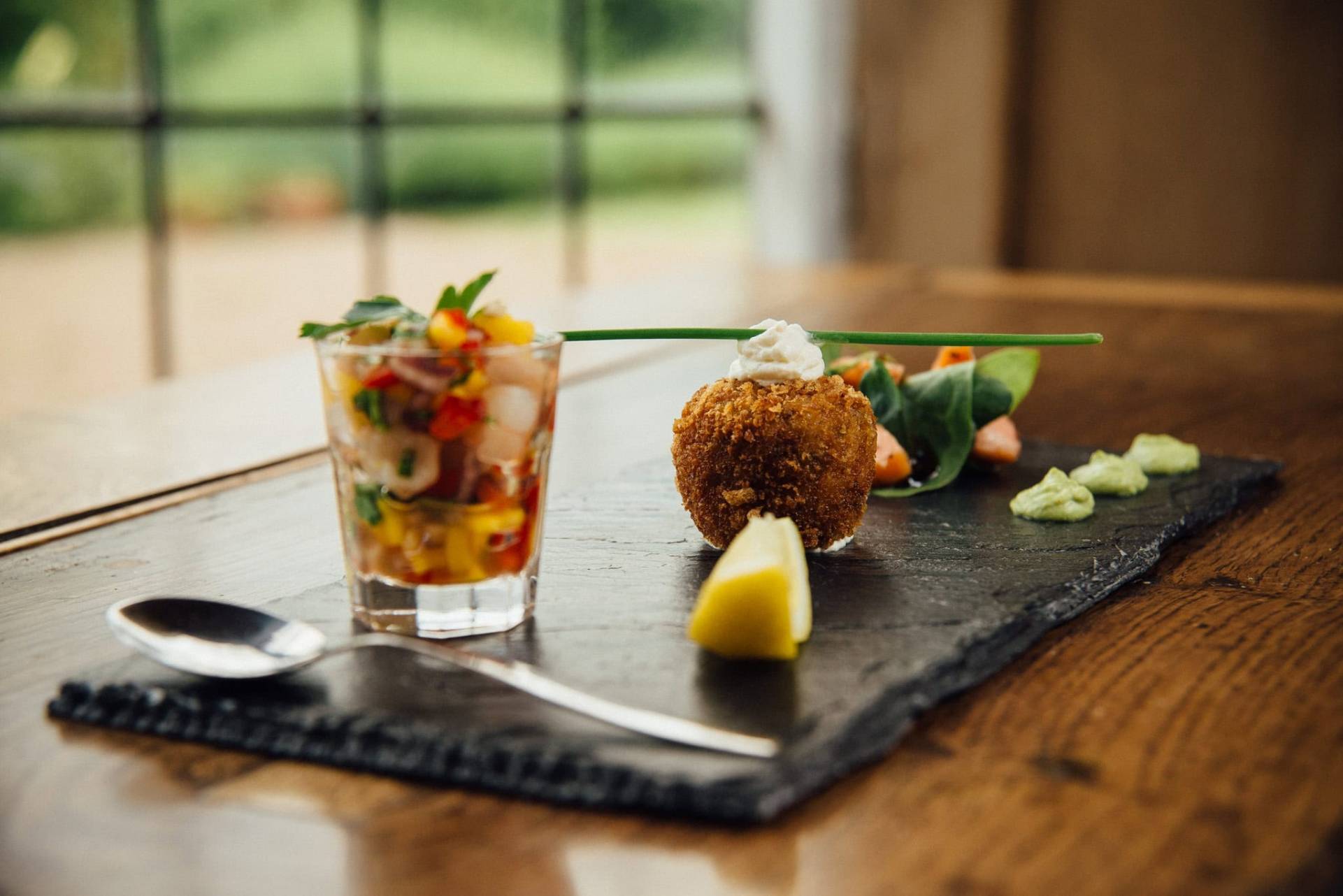 Fresh seafood dish with colorful chopped vegetables and crispy croquette on a slate platter, perfect for gourmet dining.